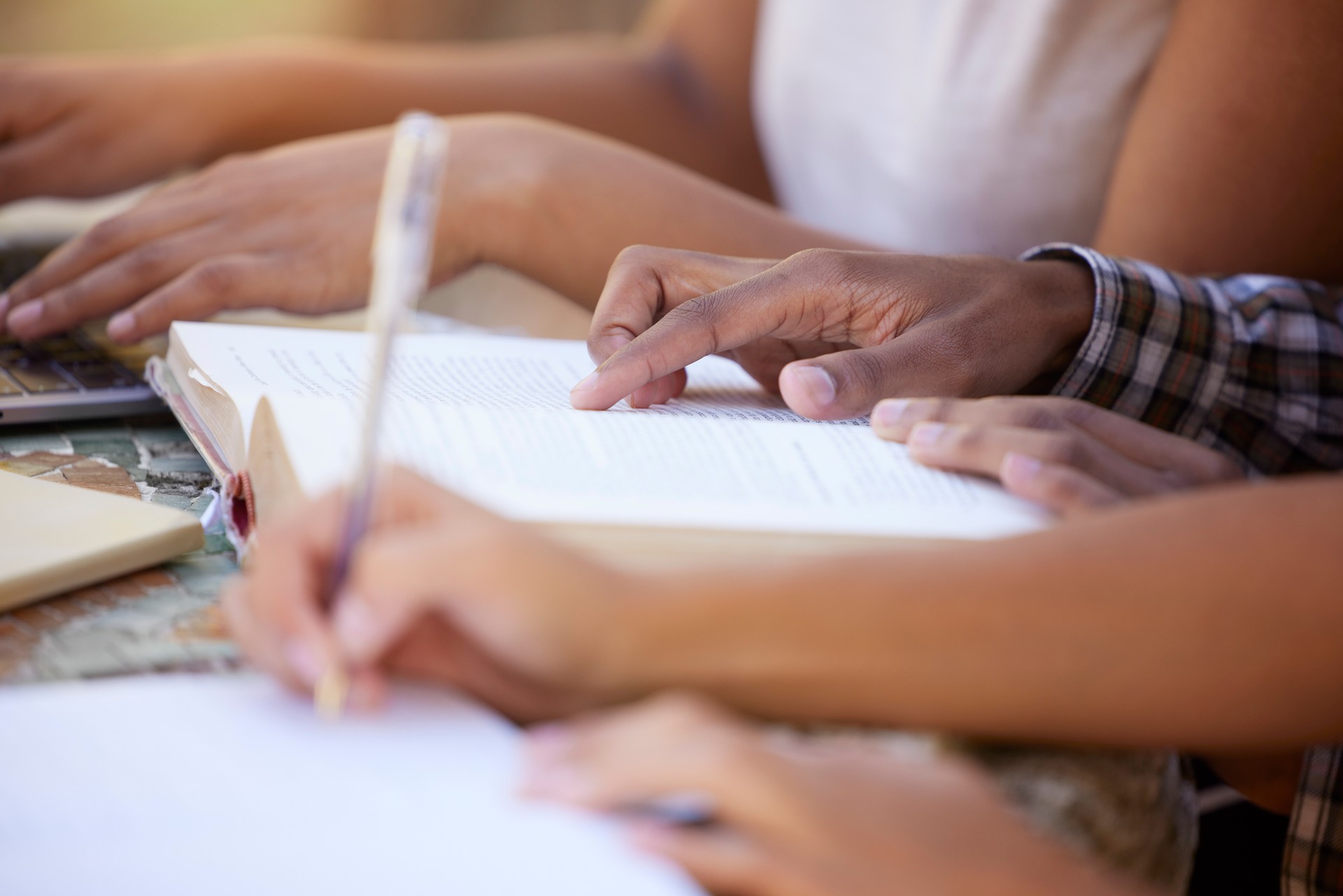 Students, education and hands writing in notebook for learning, exam studying and write notes in classroom. University, college and learners in study group for knowledge, academic course and research